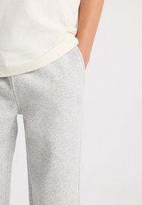 Gray cotton sweatpants with a relaxed fit, featuring a subtle textured pattern and an embroidered logo on the left hip.