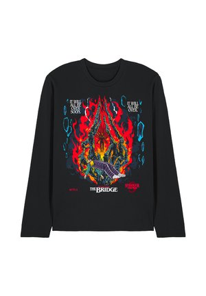Black long-sleeve shirt featuring a graphic of a person held by fiery skeletal hands, flames, and text from Stranger Things chapter "The Bridge."