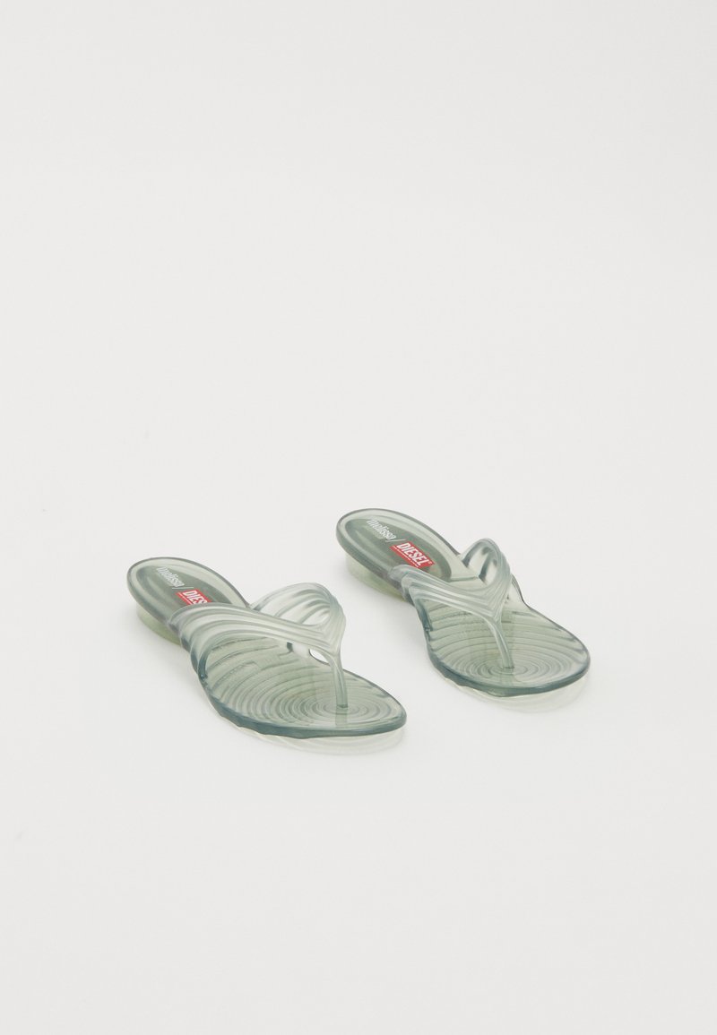 Transparente gelé-sandaler med en bølgete design, med en tårem og mønstret såle. Fargene inkluderer lysegrønn og klare toner.
