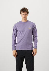 Long-sleeve, light purple cotton t-shirt featuring a mountain graphic and text "SNOW PEAK" on the left chest. Relaxed fit, round neckline.