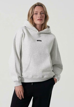 Grå hettegenser laget av myk stoff, med en frontlomme og et lite svart logo-plagg på brystet. Avslappet passform.