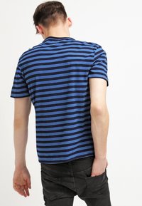 Blå och marinrandig kortärmad t-shirt med rundad halsringning, tillverkad av mjukt tyg, med avslappnad passform och rak fåll.