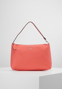 Sac à épaule en cuir texturé corail avec plaque logo "GUESS" en argent et une bandoulière à bordure noire, présenté sur une surface blanche.