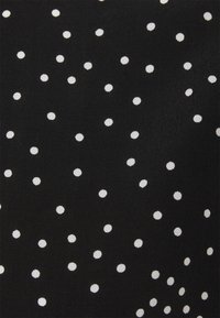 Tissu noir avec un motif irrégulier de petits pois blancs éparpillés sur la surface.
