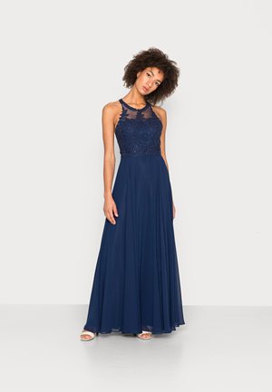 Marinblå aftonklänning med en pärlbesatt bodice med intrikata mönster, skräddarsydd kjol och ett genomskinligt halsringning. Flödande tyg skapar elegans.