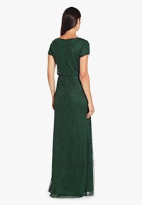 Robe maxi fluide verte avec manches courtes, présentant un motif texturé et des embellissements en perles. Fermeture éclair au dos. Superposition fine et transparente.