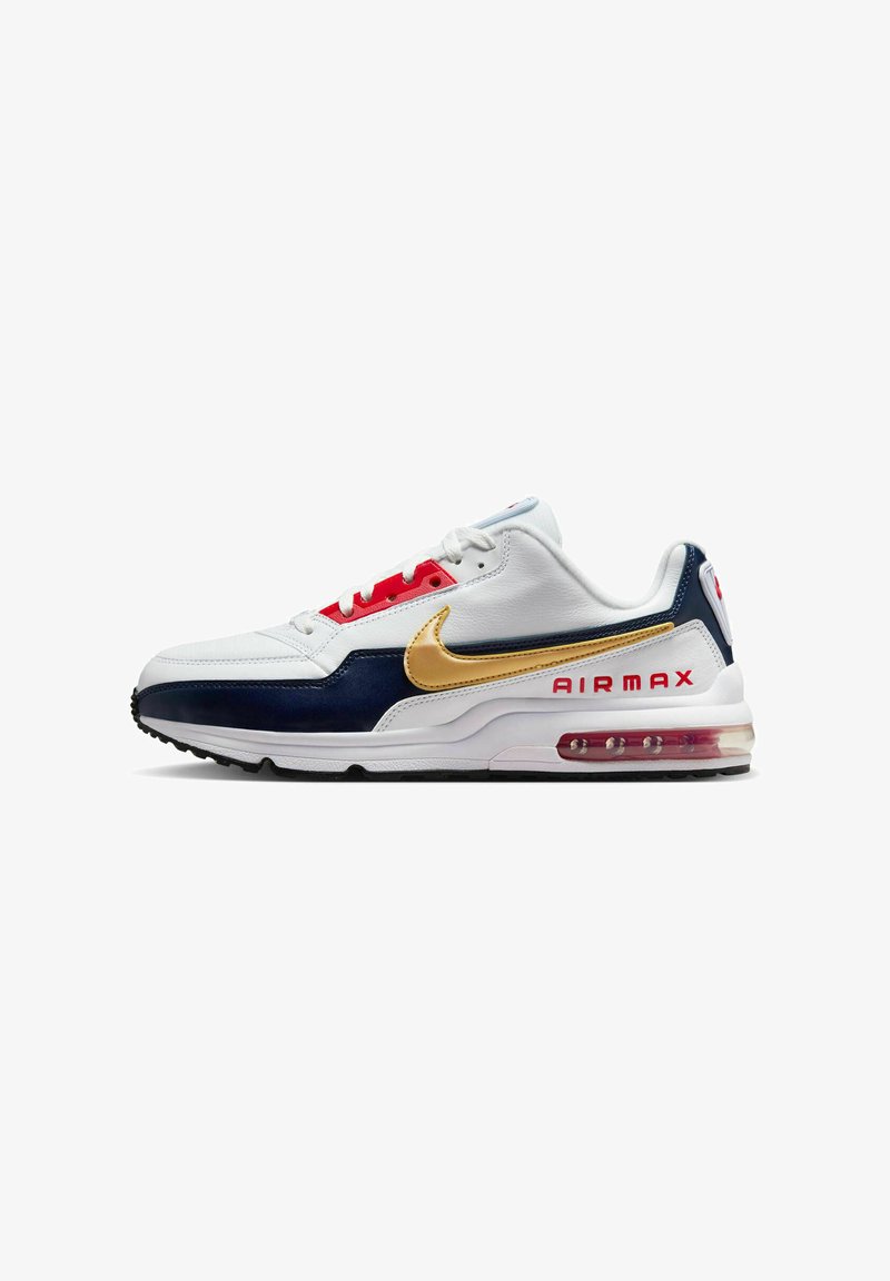 Les sneakers Nike Air Max présentent un dessus en cuir blanc avec des accents bleu marine et rouge, un swoosh doré et une unité de coussin d'air visible au niveau du talon.