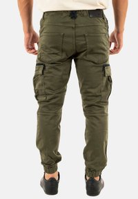 Pantalons cargo vert olive en tissu durable, dotés de plusieurs poches, de détails zippés et de poignets ajustés aux chevilles.