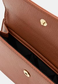 Portafoglio in pelle marrone con texture, dotato di chiusura a scatto, che presenta un ampio scomparto interno foderato in tessuto nero.
