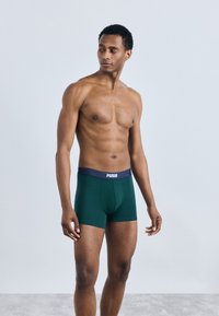 Πράσινα μποξεράκια φτιαγμένα από μαλακό ύφασμα με εφαρμοστό σχέδιο. Διαθέτουν αντίθετο ναυτικό μπλε λάστιχο με το λογότυπο "PUMA".