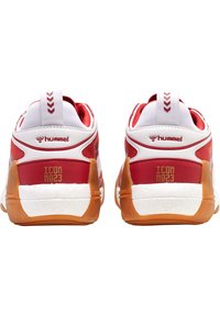 Baskets de sport rouges et blanches avec une finition texturée, dotées d'un contrefort haut, d'une semelle en caoutchouc et de détails de marque à l'arrière.