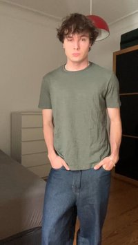 Green cotton t-shirt with short sleeves, paired with thick blue denim jeans. Natural texture, casual fit, no visible patterns or accents.