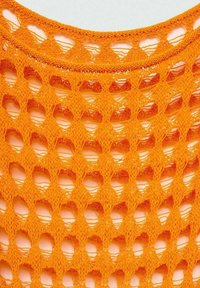 Tissu tricoté orange vif avec un motif ajouré en forme de losange et un col rond visible sur un fond clair.