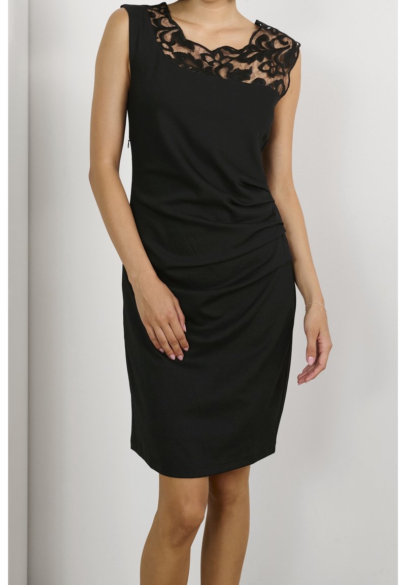 Robe noire avec un col en dentelle, sans manches, et des détails froncés sur le côté pour plus de texture. Finition en tissu lisse.