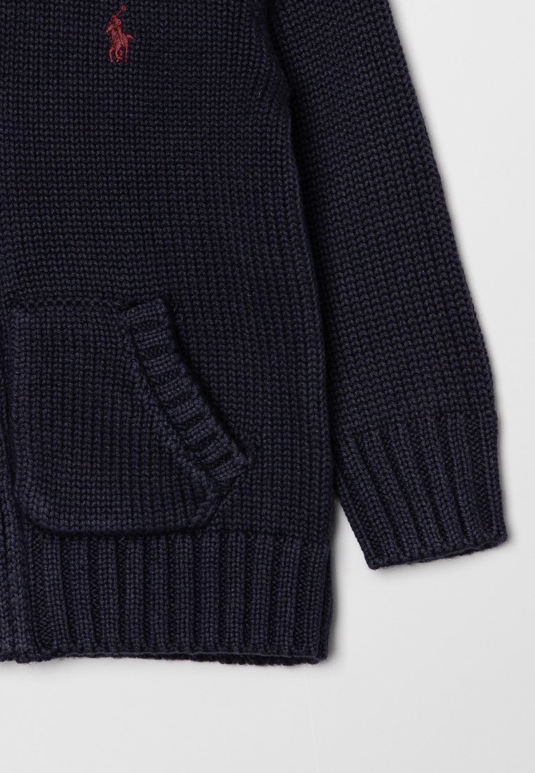 Marineblauer gestrickter Pullover mit gerippten Bündchen und Saum, Fronttasche und rotem gesticktem Polo-Spieler-Logo auf der Brust.