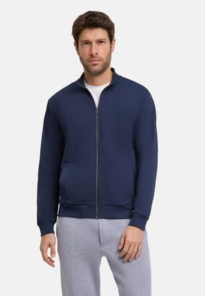 Granatowy sweatshirt na zamek wykonany z miękkiego materiału, z wysokim kołnierzem, dwoma bocznymi kieszeniami, ściągaczami przy mankietach oraz dopasowanym dołem.