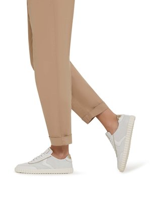 White mesh sneakers with light beige accents, featuring a textured sole and lace closure, paired with rolled beige pants.