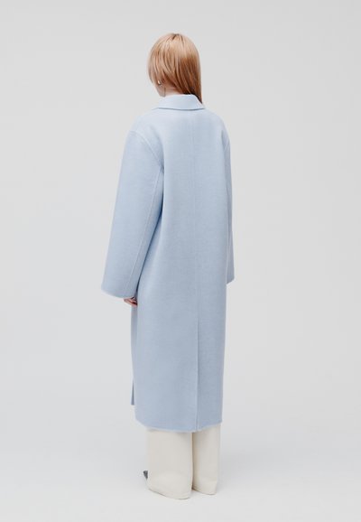 Cappotto in misto lana azzurro chiaro con silhouette dritta, maniche lunghe e colletto a rever, mostrato dal retro. Design semplice e minimalista.