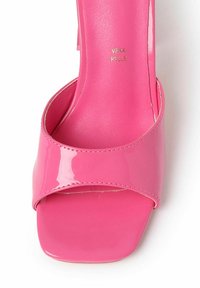 Roze gepatenteerd leren sandalen met hakken, voorzien van een brede kruisband en een vierkante neus. Gladde textuur en subtiele gouden branding op de binnenzool.