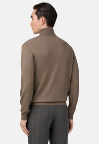 Hnedý rolák so žebrovaným golierom a manžetami, skombinovaný so šedými kockovanými nohavicami. Textúra sa zdá byť jemná a priliehavá.