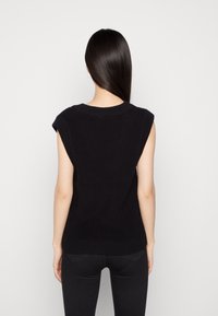 Svart stickad ärmlös topp med rundad halsringning och ribbat mönster. Har korta ärmar och en figurnära passform.