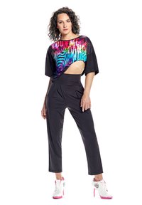 Čierny kroptop s farebným zebra vzorom a výrezom na boku, skombinovaný s čiernymi nohavicami na mieru. Model má na sebe biele a ružové lodičky na vysokom opätku.