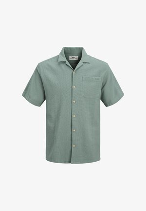 Camisa de botones verde de manga corta hecha de tejido texturizado, que presenta un bolsillo en el pecho y botones de madera clara.