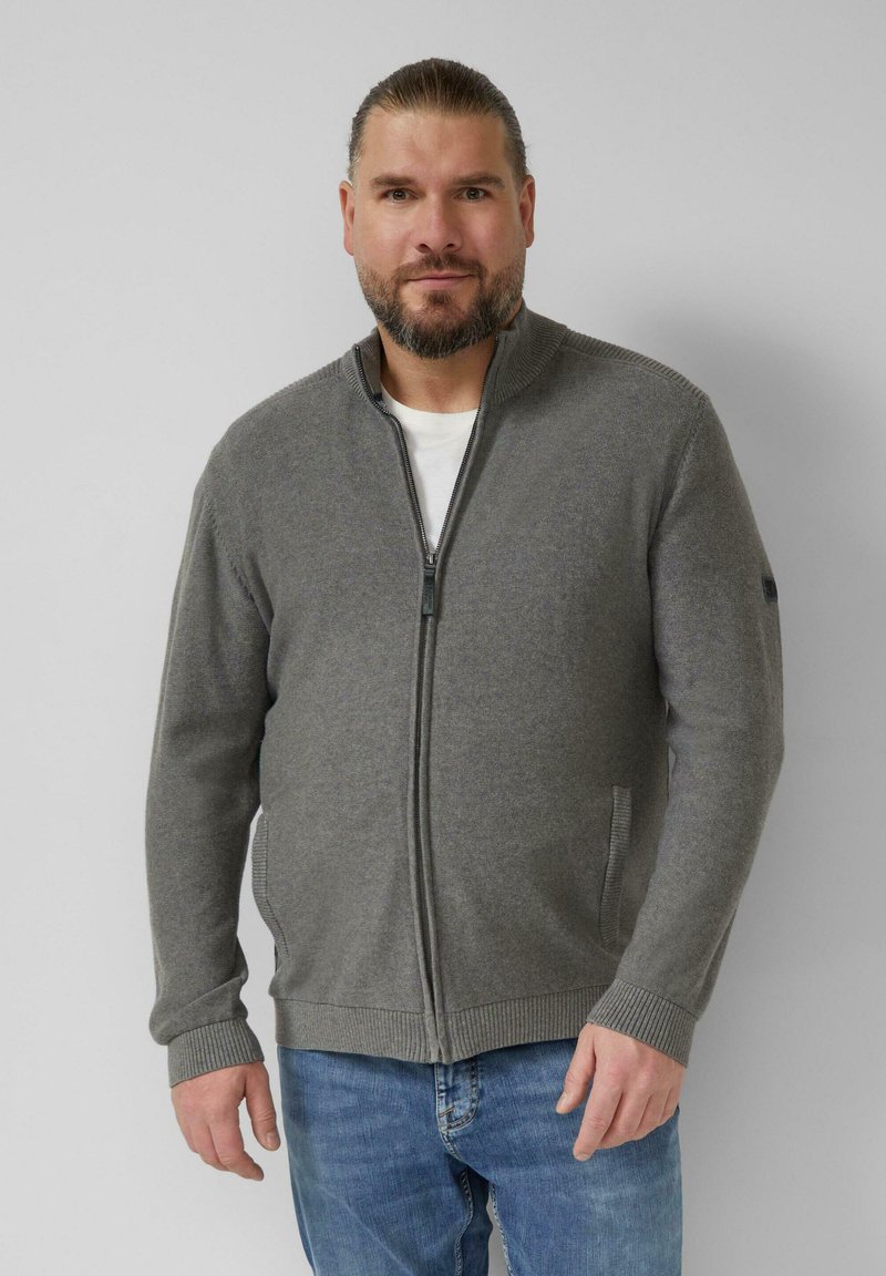 Grauer Zip-Up-Cardigan aus weichem Stoff, mit hohem Kragen, gerippten Bündchen und seitlichen Taschen. Trägt man über einem weißen T-Shirt.