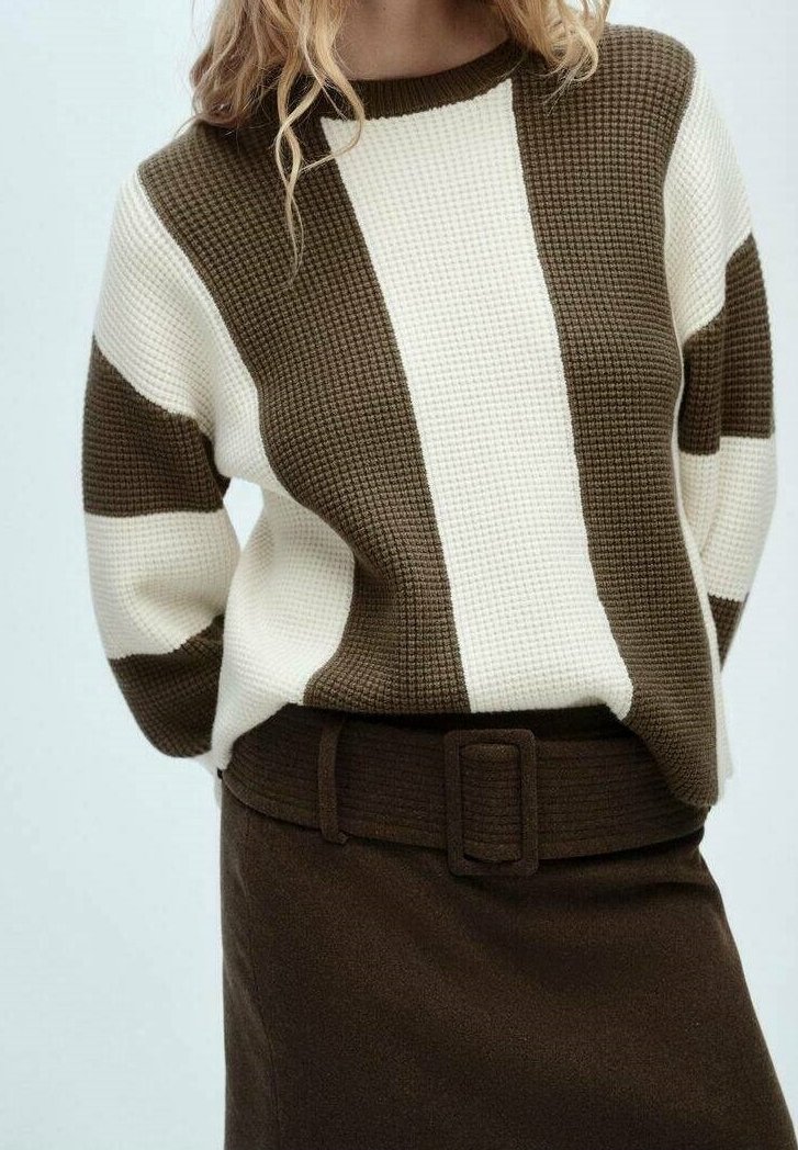 Pull en maille marron et blanc avec un motif texturé et de larges rayures, associé à une jupe marron ajustée avec une ceinture et une boucle carrée.