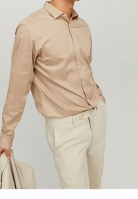 Beige overhemd met lange mouwen, een button-down kraag, een gladde textuur en knopen aan de voorkant; gecombineerd met lichtbeige broek.
