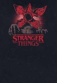 T-shirt nero con una grafica rossa che presenta un grande fiore stilizzato con mani, e il testo "STRANGER THINGS" in grassetto sotto.