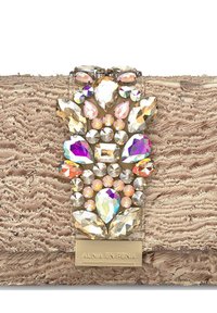 Clutch beige con una superficie de tela texturizada y un gran embellecimiento de cristal colorido en el centro, con varias formas y tamaños.