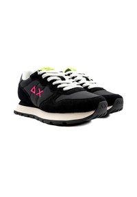Sneaker in suede e mesh neri con lacci bianchi, un logo rosa sul lato e una linguetta verde neon. Presentano una suola intermedia bianca a contrasto.
