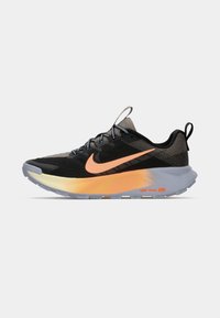 Zwarte en olijfgroene Nike trail hardloopschoen met oranje swoosh en een geel-oranje gradient middenzool op een grijze buitenzool, zijaanzicht.