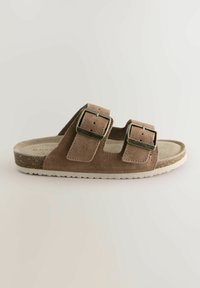 Bruna mocka slip-on sandaler med två justerbara metalldetaljer, texturerad fotbädd och lätt vit gummisål.