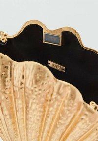 Golden scalloped handbag with a textured exterior, black interior lining, and metal accents including a tag and clasp.