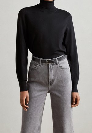 Schwarzer Rollkragenpullover kombiniert mit hoch geschnittenen grauen Jeans und einem grauen Gürtel. Die Jeans haben ein klassisches Fünf-Taschen-Design und gerades Bein.