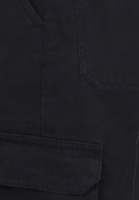 Pantalons cargo noirs en coton résistant, avec poches latérales et arrière, couture visible, et coupe décontractée avec un design à jambe droite.