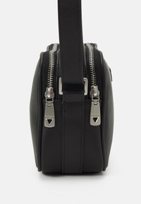 Borsa a tracolla nera in materiale sintetico con doppie cerniere, finitura texturizzata e una singola tracolla regolabile. Presenta dettagli in metallo.