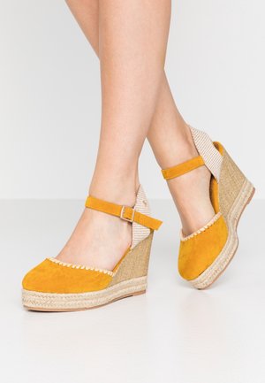 Chaussures compensées en daim jaune avec semelle en jute tressé, bride à la cheville et détails en tissu à carreaux à l'arrière. Bout plat avec bordure festonnée.