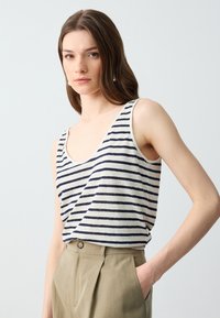 Gestreepte tanktop in lichtbeige met donkerblauwe strepen, met brede armsgaten en een ronde halslijn, gecombineerd met lichtgekleurde broeken.