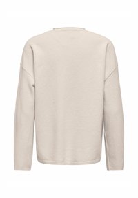 Sudadera beige clara de manga larga, con cuello redondo y un corte holgado. Tejido suave y texturizado sin patrones ni adornos visibles.