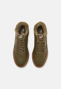Par de zapatillas Puma de color verde olivo con suelas, cordones y un suave forro interior marrón, vistas desde arriba sobre un fondo blanco.
