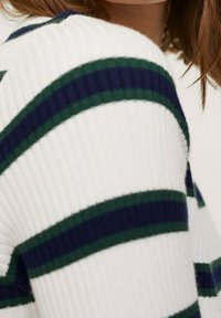 Pull côtelé avec des rayures horizontales vertes et bleu marine sur fond blanc, avec un col rond et un tissu texturé.