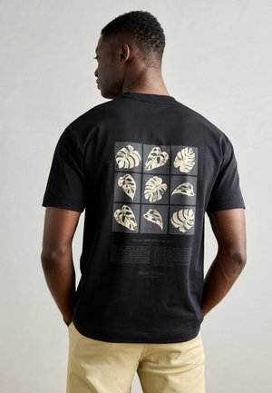 Black cotton t-shirt featuring a graphic of gold leaf patterns on the back, with text underneath and a classic crew neckline.