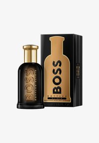 Schwarze Glas-Parfümflasche mit goldenen Akzenten, versehen mit dem erhabenen Schriftzug "BOSS". Dazu eine gold-schwarze Schachtel mit der Aufschrift "BOTTLED ELIXIR".