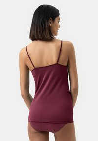 Bordowa koszulka na ramiączkach z cienkimi, regulowanymi ramiączkami i gładkim, dopasowanym krojem. Materiał ma miękką teksturę i subtelny połysk.
