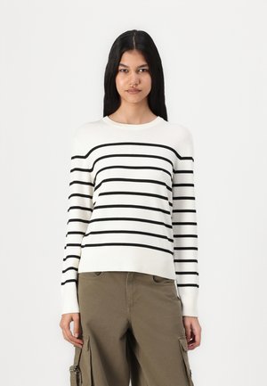 White sweater with black horizontal stripes, round neck, long sleeves, and ribbed cuffs. Paired with olive green cargo pants.
