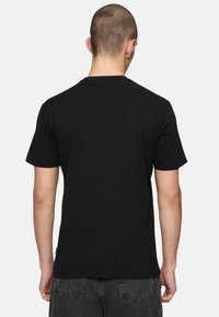 Camiseta negra de manga corta hecha de algodón, con un cuello redondo y un diseño liso. La vista trasera muestra una textura suave.