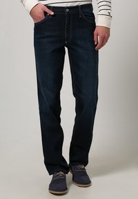 Mörkblå jeans i rak modell med femficksdesign och kontrasterande sömmar. Bärs med marinblå avslappnade skor med snörning.